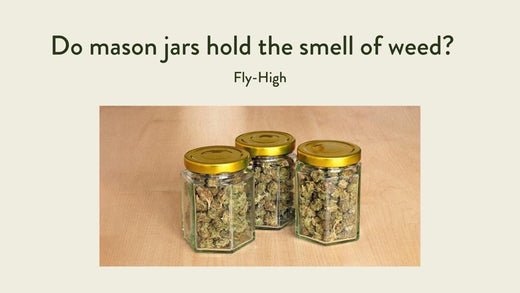 Three clear, hexagonal mason jars filled with cannabis buds, each with a golden screw-top lid, placed on a wooden surface.